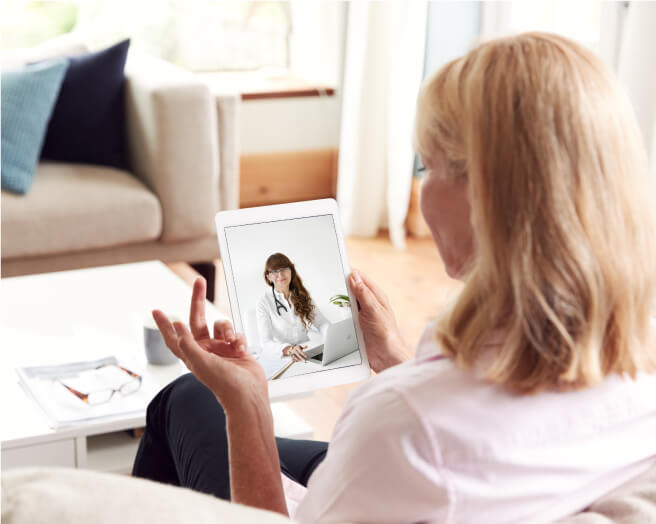 A woman at home on a video appointment, talking to a doctor on a tablet