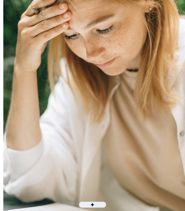 A woman in her 40s reviewing a stack of medical records at a kitchen table.